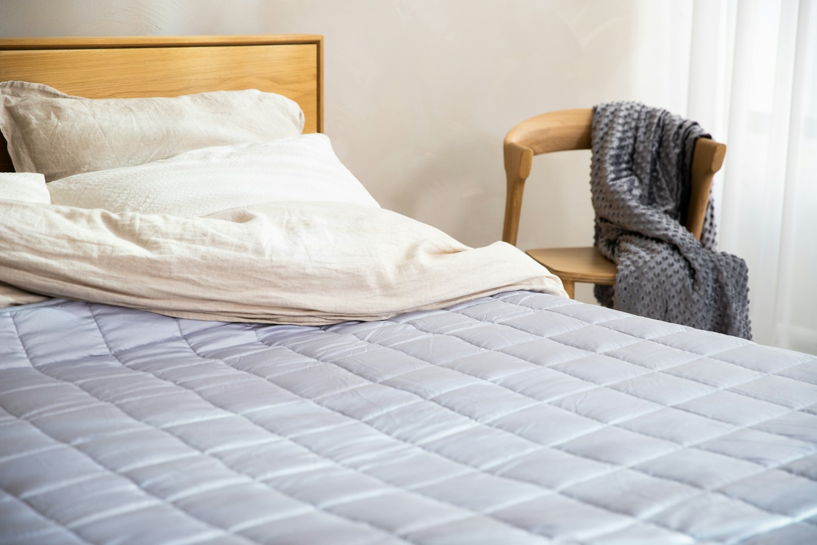 a bed with a white comforter and a wooden headboard